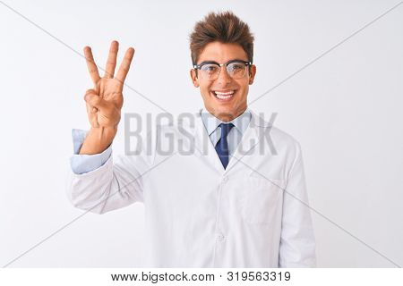 Young handsome sciencist man wearing glasses and coat over isolated white background showing and pointing up with fingers number three while smiling confident and happy.
