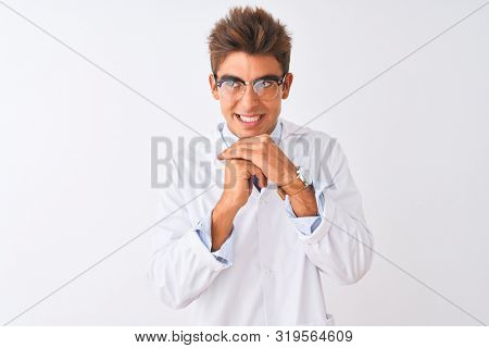 Young handsome sciencist man wearing glasses and coat over isolated white background laughing nervous and excited with hands on chin looking to the side
