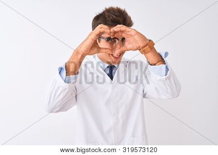Young handsome sciencist man wearing glasses and coat over isolated white background Doing heart shape with hand and fingers smiling looking through sign