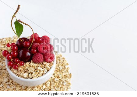 Oatmeal With Cherries, Raspberries And Red Currants In A Cup Against A White Background.
