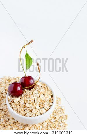 Oatmeal In A Cup Of Cherries On A White Wooden Table. There Is A Place For Your Text. The Concept Of