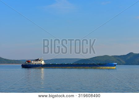 Cargo Ship Located On The Background Of The Mountains. At The Top There Is A Place For Your Text.