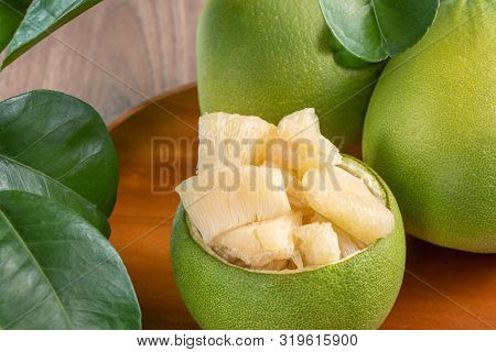 Fresh Peeled Pomelo, Grapefruit, Shaddock With Green Leaves On Dark Wooden Plank Table. Seasonal Fru