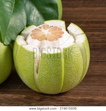 Fresh Peeled Pomelo, Grapefruit, Shaddock With Green Leaves On Dark Wooden Plank Table. Seasonal Fru