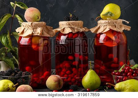 Different Of Dogwood Compote With Peaches, Pears And Blackberries In Jars On A Dark Background, Hori