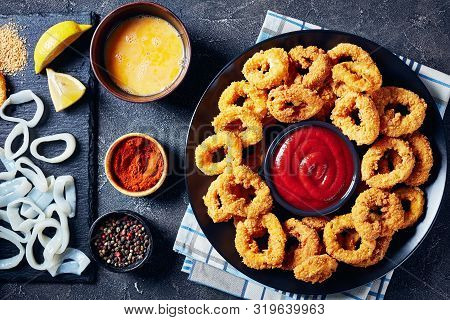 Crispy Calamari Rings, Deep Fried Breaded Squid Rings Served With Tomato Sauce On A Black Plate On A