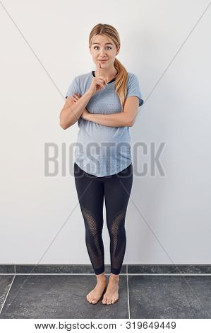 Surprised Barefoot Young Pregnant Woman Standing With Her Hand To Her Chin Raising Her Eyebrows With