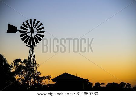 Vintage Windmill Silhouette Against Sunset. Silhouette Of House, Village, Trees