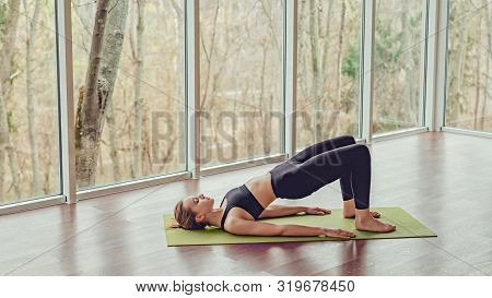 Side View Of Serene Woman Relaxing In Bridge Position While Stretching Back Muscles In Yoga Studio