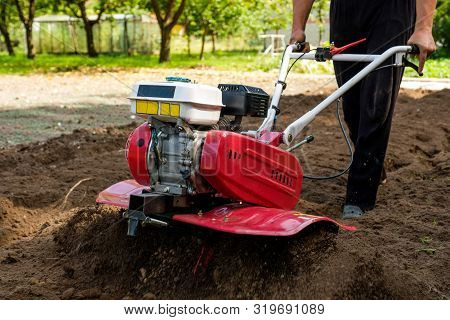 Man Working In The Garden With Garden Tiller Machine. Garden Tiller To Work, Close Up