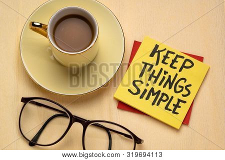 Keep things simple - handwriting on a reminder note with a cup of coffee, efficiency or minimalism concept