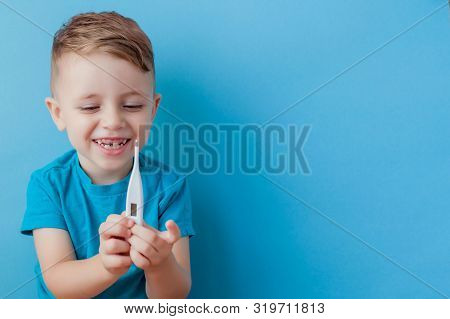 Ill Young Child With A Thermomether, Measuring The Height Of His Fever And Looking Into The Camera