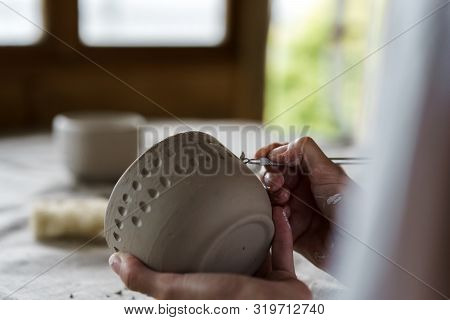 Female Hands Handle The Edge Of A Wet Clay Bowl With A Stick