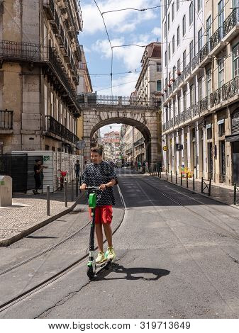 Lisbon, Portugal - 9 August 2019: Young Man Riding A Lime S Electric Scooter Along Narrow Streets Of