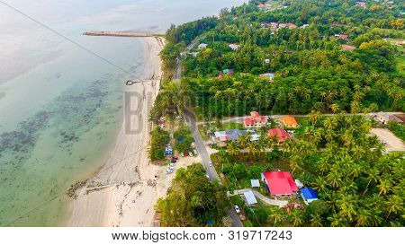 Aerial View Of Coconut Palm Trees Turquoise,houses & Sandy Beach In Pohon Batu Village,labuan Pearl 