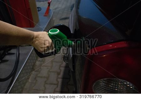 Woman Tucks Black Car At Gas Station With Her Hand At The Night