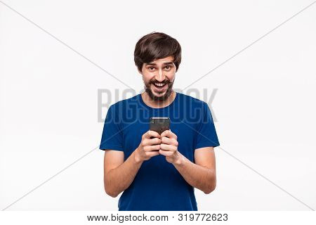 Pretty Brunet Man In A Blue Shirt With Beard And Mostaches Shocked Holding Smartphone Looking At The