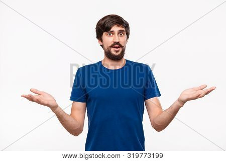 Handsome Brunet Man In A Blue Shirt With Beard And Mostaches Shrugging His Shoulders Being Clueless 