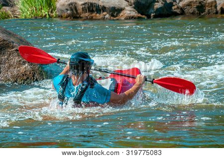 Playboating. A Man Sitting In A Kayak With Oars In His Hands Performs Exercises On The Water. Kayaki