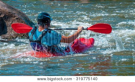 Playboating. A Man Sitting In A Kayak With Oars In His Hands Performs Exercises On The Water. Kayaki