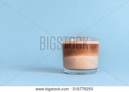 Mini Cup Of Multilayer Coffee In A Glass Cup On Blue Background
