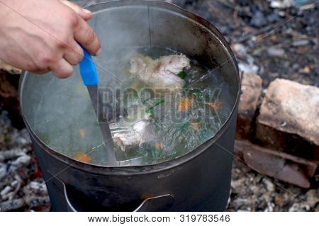 The Cook Stirs The Broth. Cooking Soup In Nature. Cooking At The Stake.