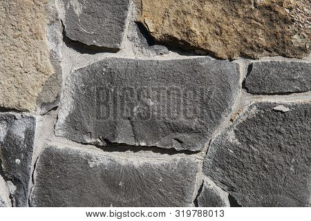 Decorative Wall Of Artificial Torn Stone In Brown Tones. Stone Masonry In Geometric Pattern As Backg