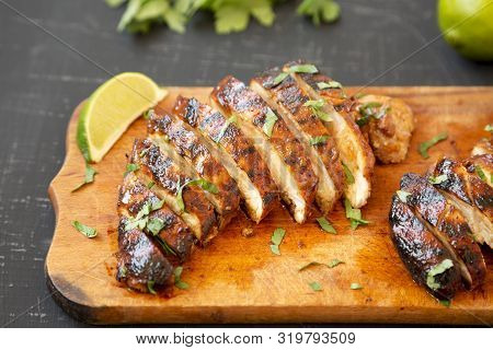 Grilled Chipotle Chicken Breast On A Rustic Wooden Board On A Black Surface, Side View. Close-up.