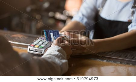 Female Customer Holding Credit Card Near Nfc Technology On Counter