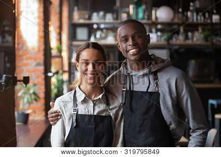 Happy Diverse Waiter And Waitress Looking At Camera In Restaurant