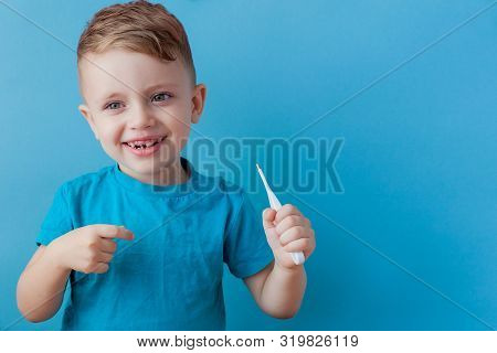 Ill Young Child With A Thermomether, Measuring The Height Of His Fever And Looking Into The Camera