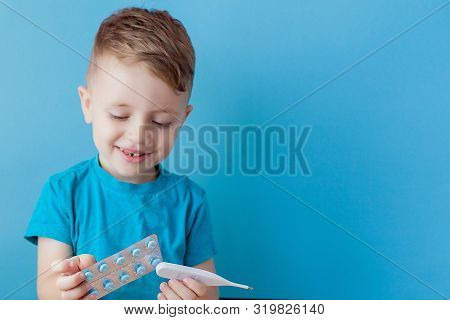 Ill Young Child With A Thermomether, Measuring The Height Of His Fever And Looking Into The Camera