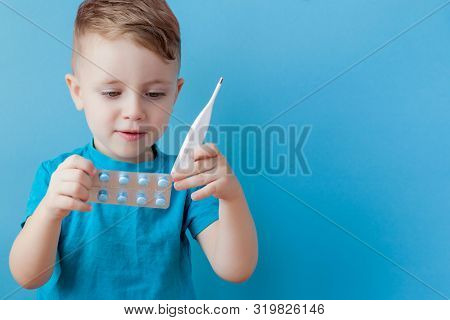 Ill Young Child With A Thermomether, Measuring The Height Of His Fever And Looking Into The Camera