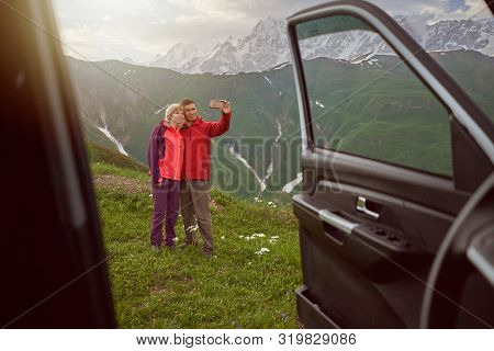 Happy Couple Making Selfie By Sell Phone On Beautiful Nature And Mountains Out Of Car