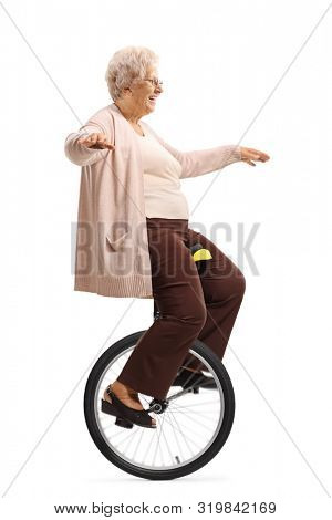 Full length profile shot of a cheerful senior lady on a mono-cycle isolated on white background