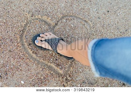 The Concept Of Loveless Love And A Broken Heart. Female Foot Crushes A Heart Made Of Sand