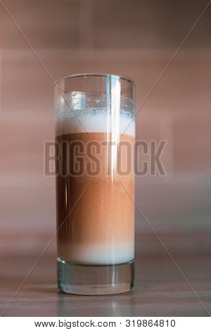 Cup Of Multilayer Coffee In A Glass Cup On Brick Background