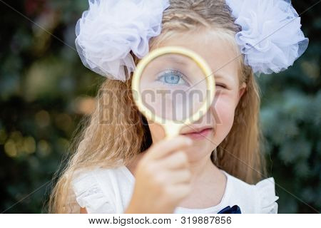 Portrait Of Beautiful Young Schoolgirl Looking Through Magnifying Glass