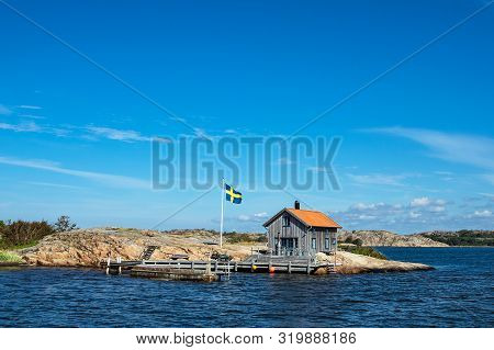 Cottage And Flag On The Island Valoen Near The City Fjaellbacka In Sweden.