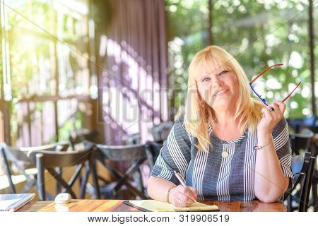 Portrait Of Beautiful Plus Size Middle Age Woman Working And Making Notes To Her Diary. Elegant Midd