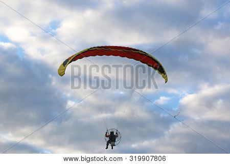 Paramotor Flying In A Blue And Cloudy Sky