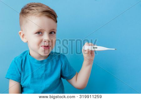 Ill Young Child With A Thermomether, Measuring The Height Of His Fever And Looking Into The Camera