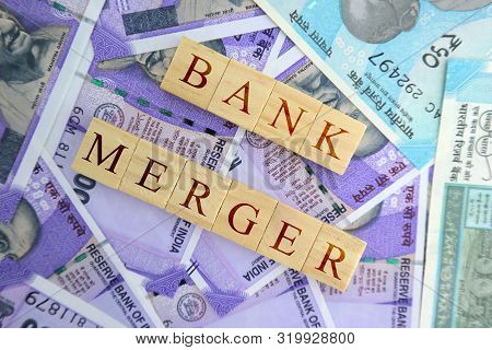 Concept Of Bank Merger In Wooden Blocks On Indian Currency Notes.