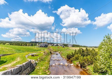 Sunny Summer Day In Jizerka Mountain Village. Jizerka River, Green Meadows And Blue Sky With White C