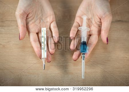 Flu Shot. Doctor Woman Holding In Hands Thermometer With A High Temperature And A Syringe With Vacci