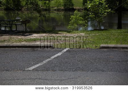 White Line Dividing Parking Spaces In Front Of A Small Pond
