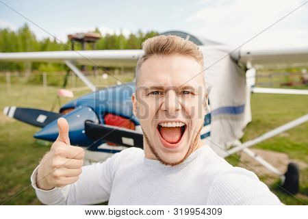 Happy Male Pilot Selfie Photo Aviator Smiling On Background Propeller Driven Aircraft. Travel Rental
