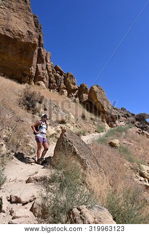 Young Woman On Misery Ridge Trail In Smith Rock State Park Near Terrebonne, Oregon On A Coudless Sum
