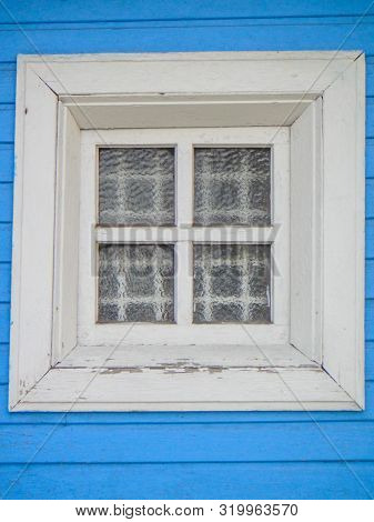 A White Wooden Window With A Lattice And A Guipure Curtain Against The Background Of A Blue Painted 