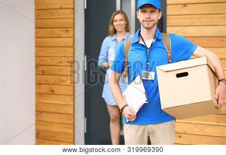 Smiling Delivery Man In Blue Uniform Delivering Parcel Box To Recipient - Courier Service Concept. S